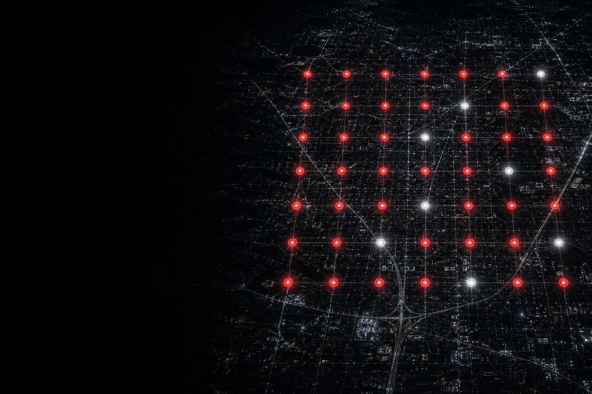 Night aerial view of a city with a Google Maps rank grid of red and white location pins overlaid